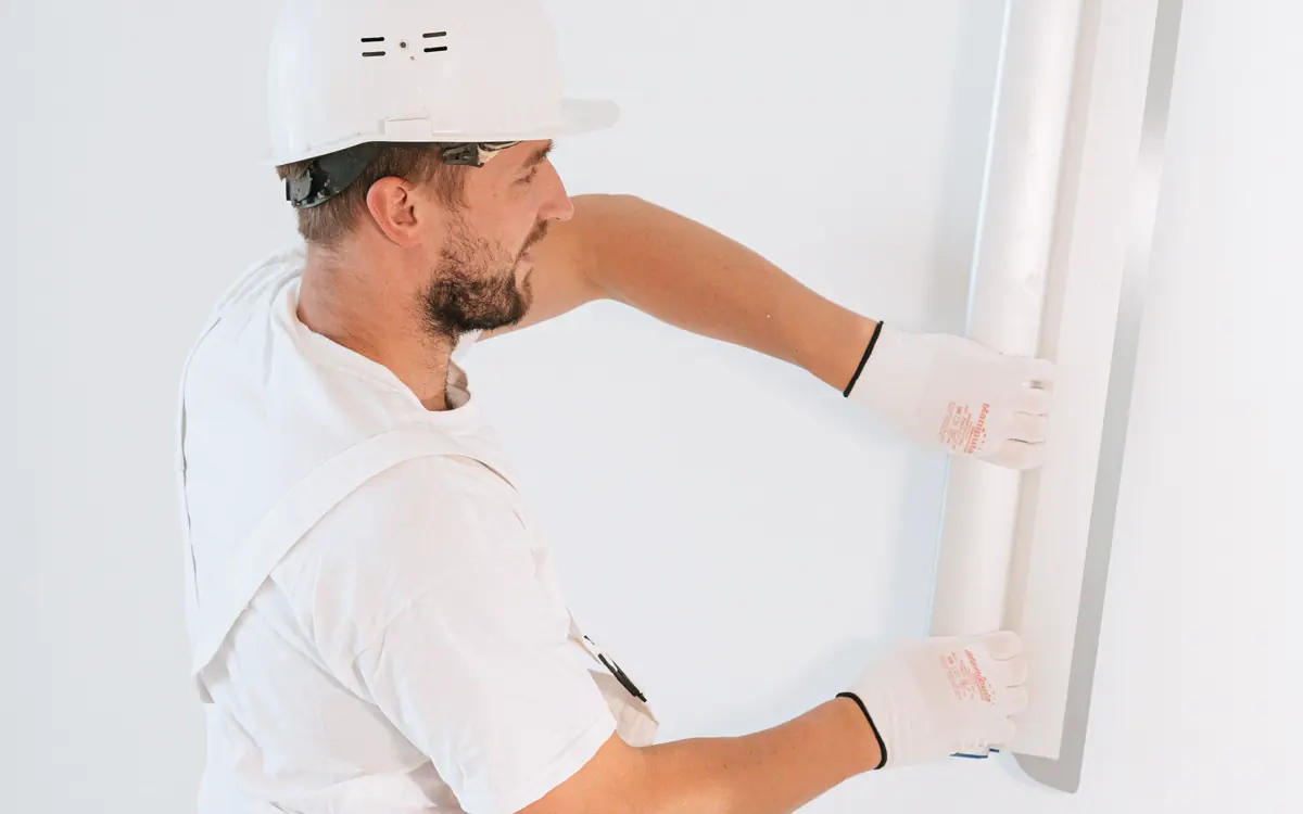 Professional installing drywall inside a bright interior